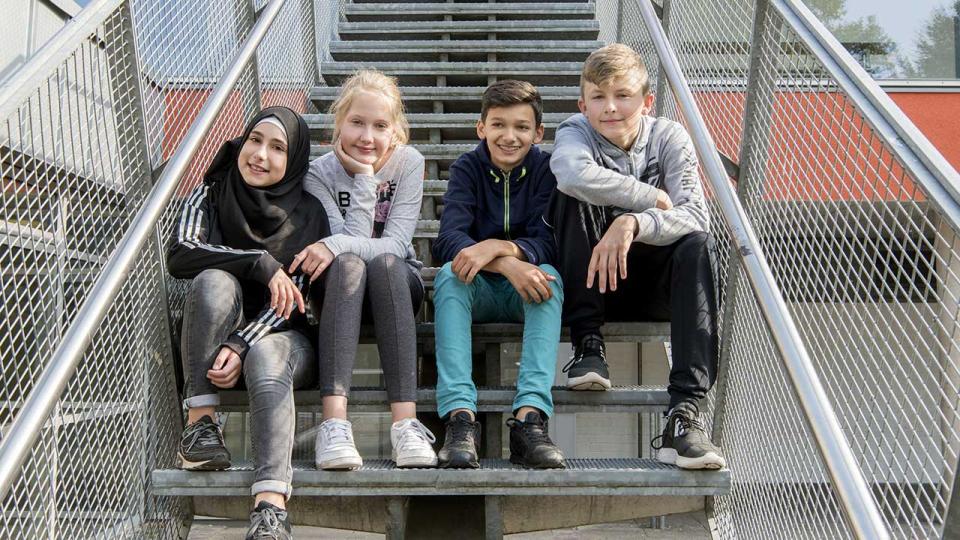 Vier Schülerinnen und Schüler sitzen auf einer Treppe