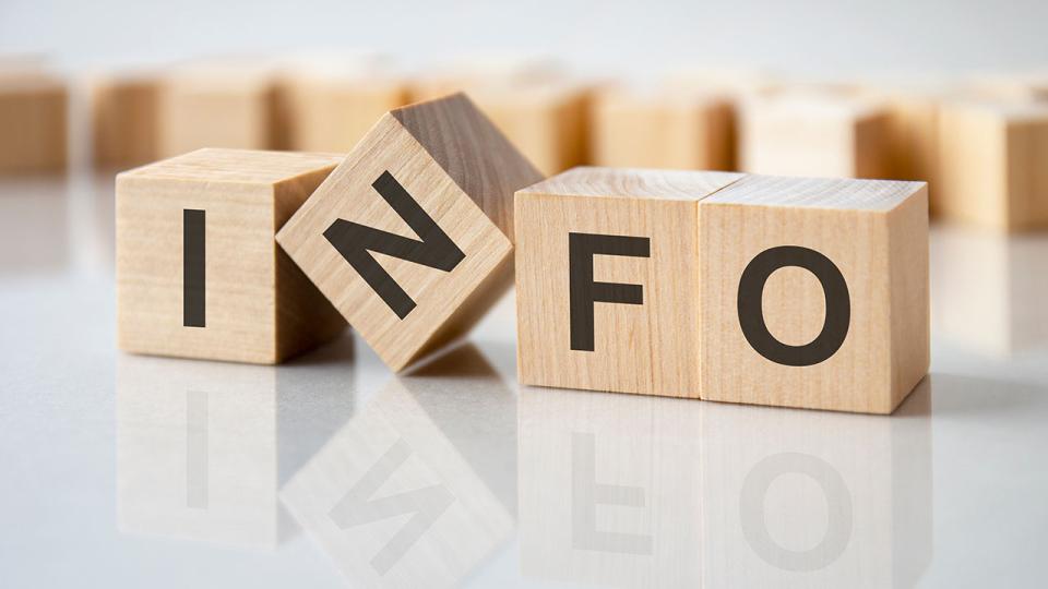 Vier Holzblöcke mit den Buchstaben Info auf der hellen Oberfläche eines grauen Tisches