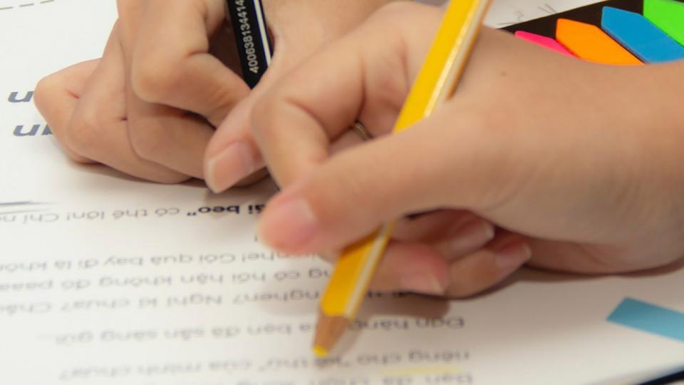 Zwei Hände malen mit Buntstiften auf einem Papier
