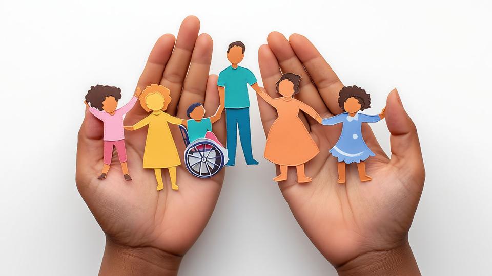 Hände, die einen Papierausschnitt einer Familie halten, die Fürsorge, Integration und Vielfalt repräsentiert
