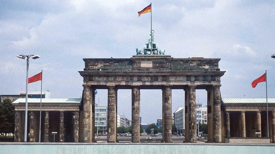 Historisches Bild vom Juli 1980: Blick von West-Berlin über die Berliner Mauer auf das Brandenburger Tor und Ost-Berlin. Schild mit der Aufschrift „Achtung: You are leaving West Berlin“ im Vordergrund. Eingescanntes Dia.