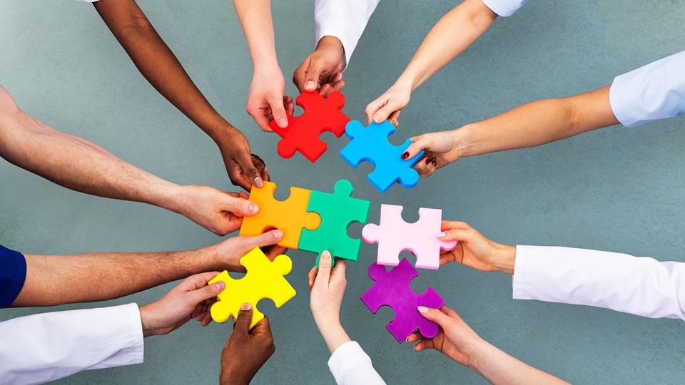 Mehrere Hände halten Puzzleteile zusammen