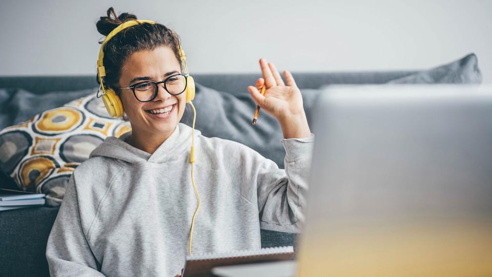 Frau mit Videoanruf auf ihrem Computer zu Hause. Lächelndes Mädchen studiert online mit Lehrer.