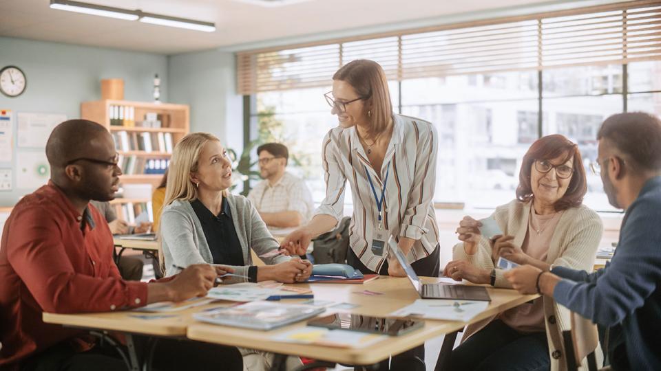Vielfältige Gruppe junger und älterer Erwachsener, die eine Lösung für eine Teamaufgabe finden und an einem Trainingsprogramm zur Verbesserung der Fähigkeiten teilnehmen.