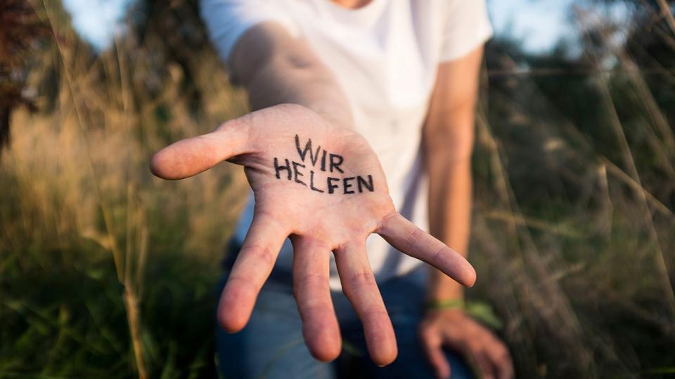 Helfende Hand, in der "Wir helfen" geschrieben steht