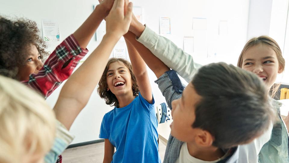 Schülerinnen und Schüler halten ihre Hände gemeinsam in der Mitte hoch