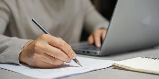 Zur Visualisierung des Menüpunktes EFV Übungen zeigt das Bild eine Person, die sich handschriftlich Notizen macht.