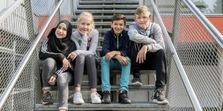 Vier Schülerinnen und Schüler sitzen auf einer Treppe