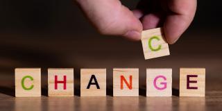 Hand setzt einen Buchstaben und zeigt, das Veränderung gleichzeitig eine Chance ist