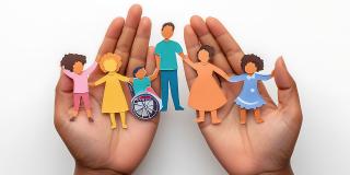 Hände, die einen Papierausschnitt einer Familie halten, die Fürsorge, Integration und Vielfalt repräsentiert
