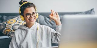 Frau mit Videoanruf auf ihrem Computer zu Hause. Lächelndes Mädchen studiert online mit Lehrer.