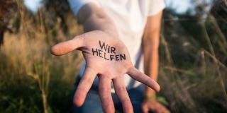 Helfende Hand, in der "Wir helfen" geschrieben steht