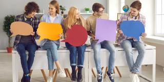 Kreative junge Menschen, Schulkameraden, Studenten halten bunte Papier Karton Sprechblasen, den Austausch von Meinungen, die Suche nach gemeinsamen Gründen, Interessen, Ideen. 
