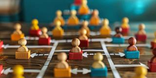 Ein Bild, das ein Holzbrett mit bunten Spielsteinen zeigt, die so angeordnet sind, dass sie ein komplexes Netzwerk oder eine Hierarchie darstellen, die wahrscheinlich eine soziale oder organisatorische Struktur symbolisieren. 