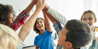 Schülerinnen und Schüler halten ihre Hände gemeinsam in der Mitte hoch