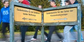 Zwei Tafeln mit Richtungsanzeige zu einer Gedenkstätte