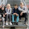 Vier Schülerinnen und Schüler sitzen auf einer Treppe