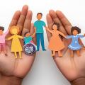 Hände, die einen Papierausschnitt einer Familie halten, die Fürsorge, Integration und Vielfalt repräsentiert