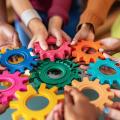 Verschiedene Charaktere versammeln sich um eine farbige Wand, die Inklusivität und Einheit in Wirtschaft und Finanzen, Teamwork und Zusammenarbeit symbolisiert.