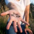 Helfende Hand, in der "Wir helfen" geschrieben steht